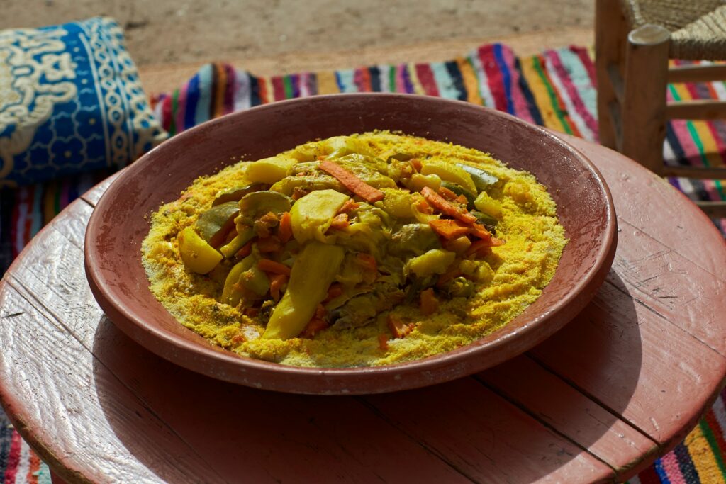 Couscous with vegetables in a red bowl.