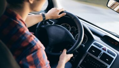Close-up view of a man driving a modern car, showing dashboard and steering details.