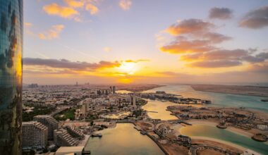 the sun is setting over a city and a body of water