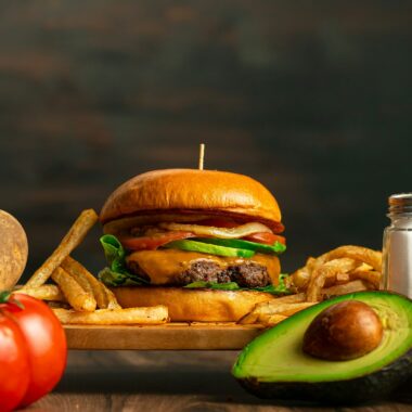 a hamburger, french fries, avocado, tomato, onion, and salt